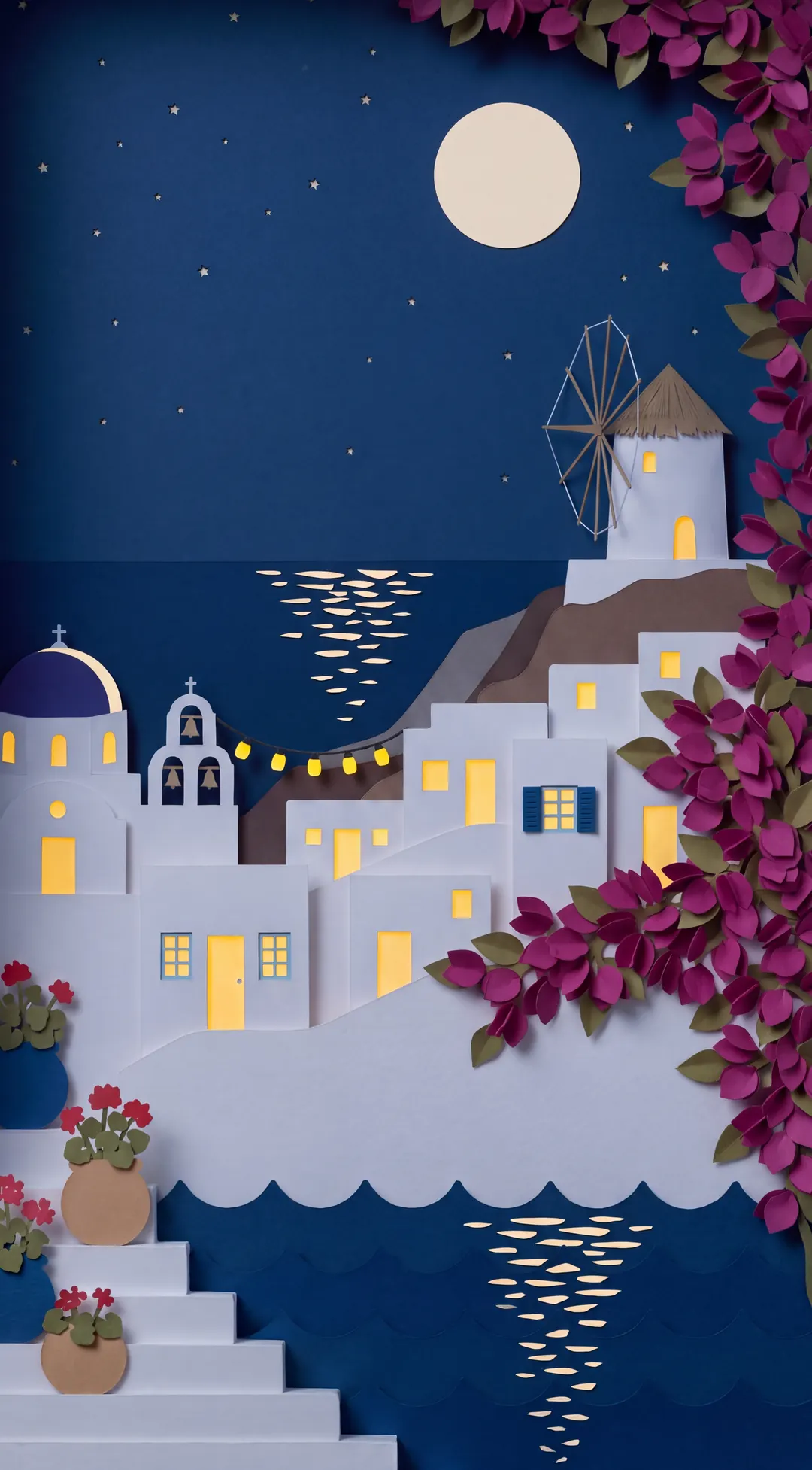 The paper village at night, its windows lit