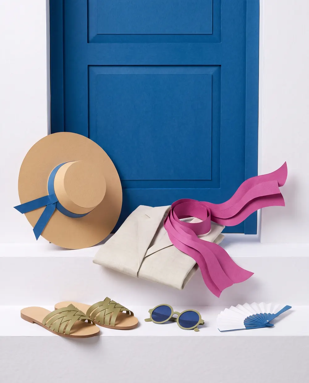 A sun hat, linen jacket, magenta scarf, sandals and sunglasses on a whitewashed ledge