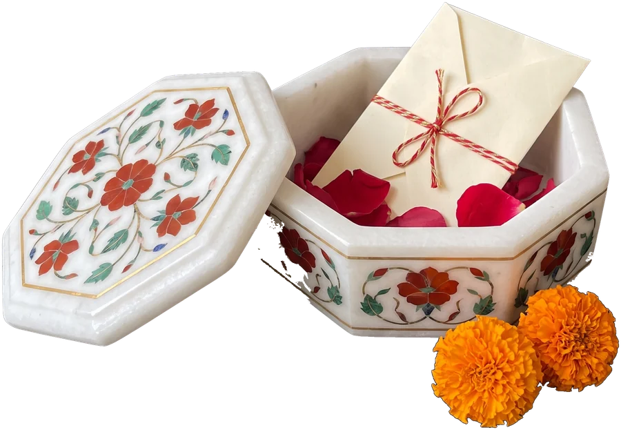 An inlaid marble keepsake box holding an envelope and rose petals